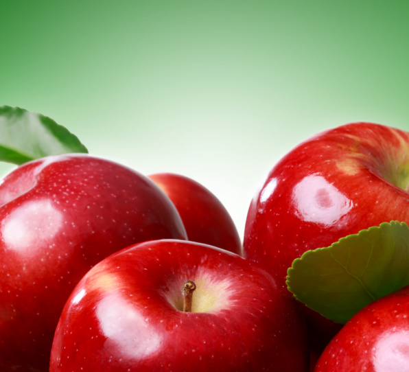 Closeup of apple with blue measuring tape holded by young sportswoman over white background